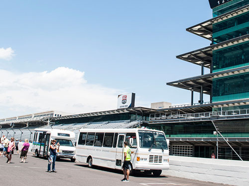 Two white buses with tourists in front of the Indianapolis Motor Speedway pagoda 